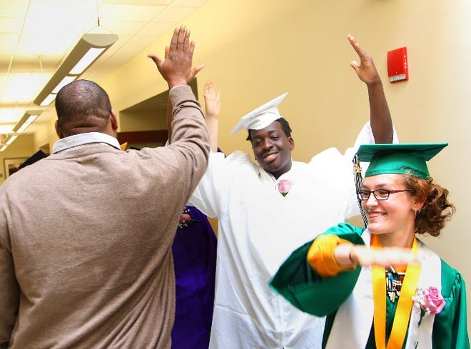 Jonathan Fanfan, of Weymouth, celebrates and Claire McAteer, of Scituate, get high fives from staff Jaumal Moore. Graduation was held at South Shore High School in Hingham on Wednesday.