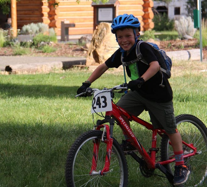 Boden Birch, 9, of Yreka, is all smiles as he crosses the finish line in the C Division race at Siskiyou Family YMCA Mountain Bike Series on Tuesday at Upper Greenhorn Park in Yreka.  Daily News Photo/Bill Choy