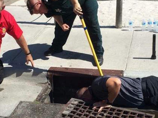 James Jorgensen, holding pole, with Polk County Animal Control, and other members of the rescue team work to save six ducklings from a storm drain on May 31.