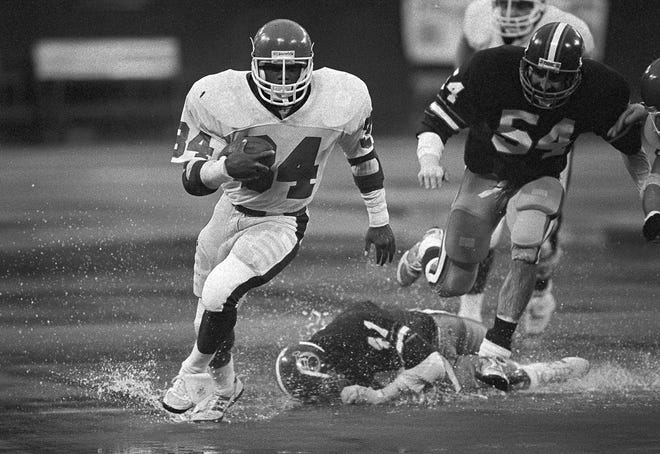 New Jersey Generals' Herschel Walker (34) splashes past Pittsburgh Maulers' defender Jeff Delaney (41) during a game in 1984. Walker ran for 152 yards in a steady rain to lead the Generals to a 14-10 win on April 22. (AP Photo/Gene Puskar)