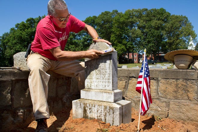 (Sarah Martin/ The Gaston Gazette) A member of the Dallas Masonic Lodge uses the tough bristles of brush to clean the tombstone of 7th Calvary member, John Campo, where lodge members are rebuilding the wall around his grave on June 6, 2015.