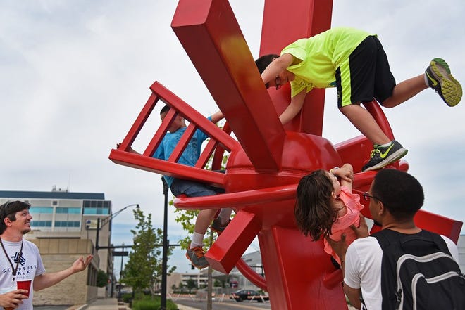 Supervised children enjoy the climbable features of artist Nathan Pierce's "Don't Forget Us" on Saturday at Sculpture Walk Peoria.