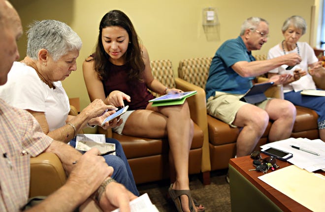 Instructor Maria Vargas helps a student download an app to her iPhone during a class teaching local seniors how to operate their Apple products Tuesday at the Senior Recreation Center in Gainesville.