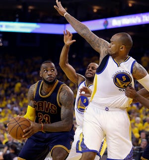 Cavaliers forward LeBron James drives on Golden State Warriors forward Andre Iguodala, center, and forward Marreese Speights during Game 2 of the NBA Finals in Oakland, Calif., Sunday. THE ASSOCIATED PRESS