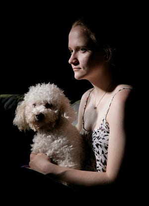In this April 2015 photo, sexual assault victim Emily Kollaritsch poses for a photo with her service dog, Candy, in East Lansing, Mich. If it weren't for Candy, Kollaritsch, who suffers from post-traumatic stress disorder, says she would not have been able to return to school. A growing backlog at the U.S. Department of Education has some sexual assault victims waiting years to have their cases resolved. (AP Photo/Al Goldis)