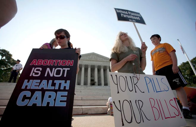 In this June 28, 2012, file photo, demonstrators pray outside the Supreme Court in Washington before a landmark decision on health care. Many Americans doubt that the Supreme Court can rule fairly in the latest litigation jeopardizing President Barack Obama’s health care law. The Associated Press-GfK poll finds only 1 in 10 are highly confident that the justices will rely on objective interpretations of the law instead of their personal opinions. Nearly half (48 percent) are not confident of the court’s impartiality. (AP Photo/Evan Vucci, File)