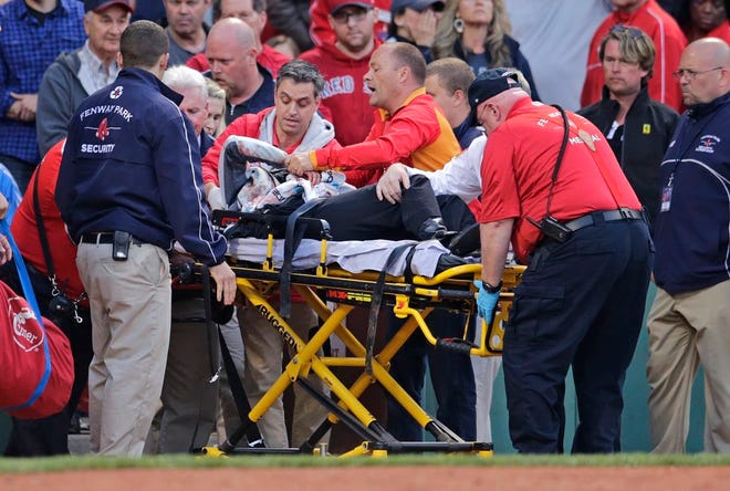 RETRANSMISSION TO CORRECT ID OF PLAYER - A fan, who was accidentally hit in the head with a broken bat by Oakland Athletics' Brett Lawrie, is helped from the stands during a baseball game against the Boston Red Sox at Fenway Park in Boston, Friday, June 5, 2015. The game was stopped while they wheeled her down the first base line. (AP Photo/Charles Krupa)