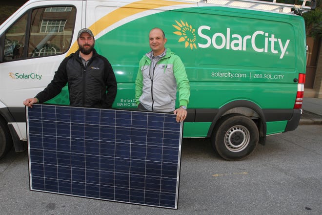 Stephen Zariczny, left, regional operations manager for SolarCity, and Lee Keshishian, regional vice president for the East Coast, stand beside a solar panel. The company, one of the nation's largest installers of residential solar-energy systems, starts business in Rhode Island on Monday.