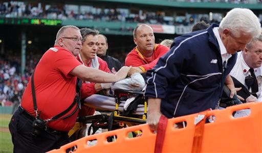 Boston Red Sox medical personnel tend to Tonya Carpenter, who with was hit by a wooden shard, off a broken bat of Oakland Athletics' Brett Lawrie, in the second inning during a baseball game at Fenway Park in Boston, Friday, June 5, 2015. The game stopped as the woman was taken from the stands on a stretcher down the first base line to a waiting ambulance. (AP Photo/Charles Krupa)