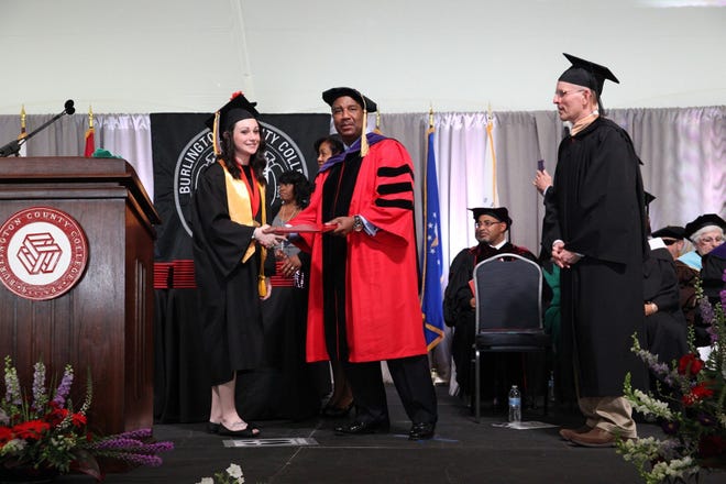 BCC’s class valedictorian Kathleen Keane accepts her degree from BCC President Paul Drayton as BCC Board of Trustees Chair George Nyikita waits to congratulate the graduate.