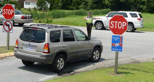 Jonathan Whitley, Lenoir County Sheriff’s deputy, directs traffic out of Woodington Middle School on Wednesday. The state DOT has approved parking lot improvements for the school, which will be done in time for the start of school in the fall.