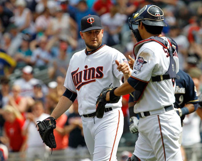 Minnesota Twins relief pitcher Glen Perkins, left, and catcher Kurt Suzuki, right, celebrates after the Twins defeated the Milwaukee Brewers 2-0 in a baseball game in Minneapolis, Sunday, June 7, 2015. (AP Photo/Ann Heisenfelt)