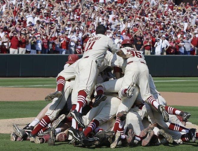 Arkansas players celebrate and pile up as fans cheer after a super regional against Missouri State in the NCAA college baseball tournament in Fayetteville, Ark., Sunday, June 7, 2015. Arkansas defeated Missouri State 3-2.