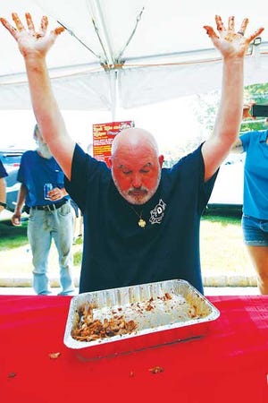 Photo by Tracy Klimek/New Jersey Herald/Ringwood’s Skyline Lakes firefighter Jeff Walsh raises barbecue- sauce-covered hands on Saturday after finishing a rack of ribs in two minutes and eight seconds.