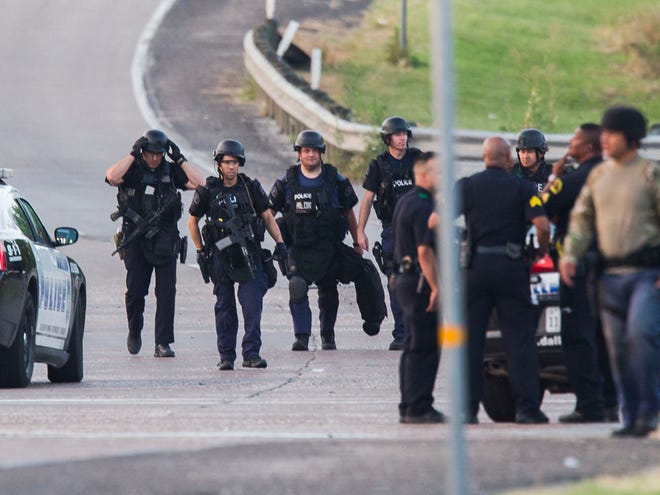 Dallas SWAT and other police officers gather at the intersection of Interstate 45 and E Palestine Street, where police have cornered a suspect in a van on Saturday, June 13, 2015 in Hutchins, Texas. Police Chief David Brown says a police sniper has shot the suspect in an overnight attack on police headquarters and that the department is checking to see if he's still alive. Brown says investigators believe the man acted alone in the early-morning attack on Dallas police headquarters, despite early witness reports that others may have taken part.