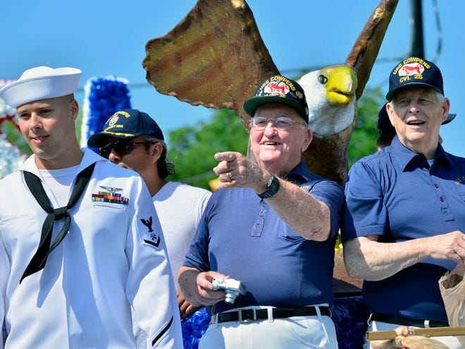 Carswell Wynne, center, president of the USS Cowpens Reunion Association and Navy veteran who served on the USS Cowpens CVL-25, smiles from the Town of Cowpens float as people cheer and take photos during the 37th Annual Mighty Moo Festival parade held Saturday, 14, 2014 in downtown Cowpens.