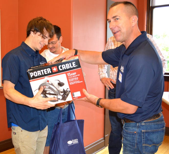 Josh Foster, left, a new trainee at Taking Root Ministries, recieves Monday, June 15, from an Elzinga Volkers employee a circular saw and bag of essetial tools and safety supplies to get him started in the construction industry. Annette Manwell/Sentinel staff