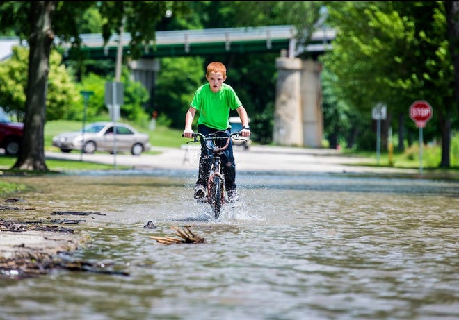 The Illinois River was more than two feet over flood stage at Henry Tuesday afternoon as the river is expected to keep rising for the next few days. For Zachary Wehr, 8, that just meant going down Cromwell Drive on a bike was just a bit more fun.