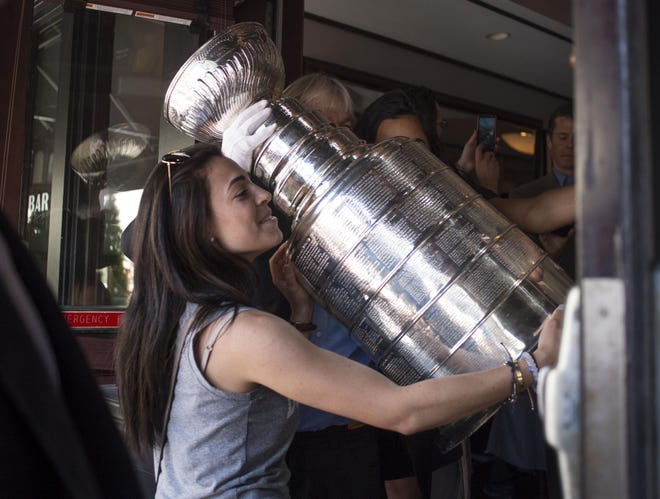 A Chicago Blackhawks fan hugs the Stanley Cup trophy as it made a stop at Phil Stefani's 427 restaurant Tuesday, June 16, 2015, in downtown Chicago, the day after the Chicago Blackhawks captured their third NHL title in six years. (Saiyna Bashir/Sun-Times Media via AP)