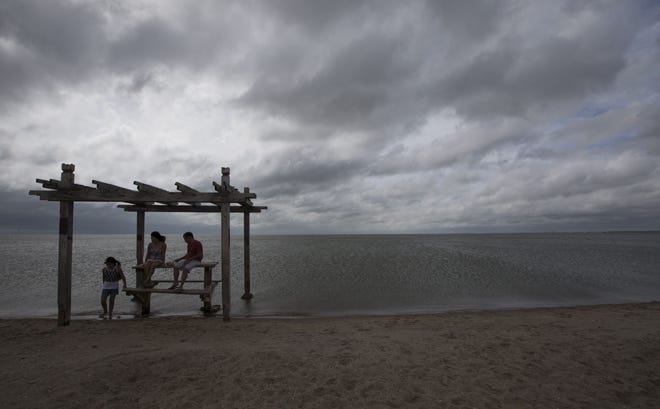 Jenny E. Phan, Tri Phan and Van Phan visit North Beach on Tuesday in Corpus Christi, Texas. The Associated Press