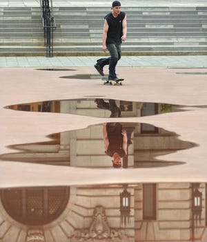 WORCESTER - A skateboarder is reflected in puddles on the Worcester Common Oval Tuesday afternoon. T&G Staff/Christine Peterson