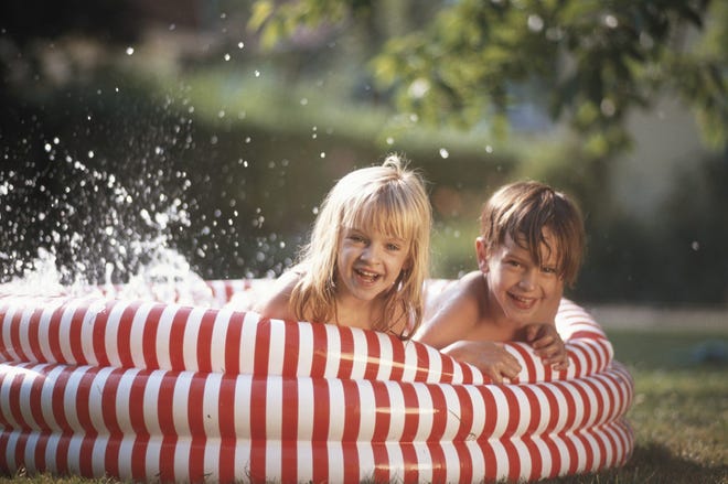 Girl and boy (4-7) lying in paddling pool