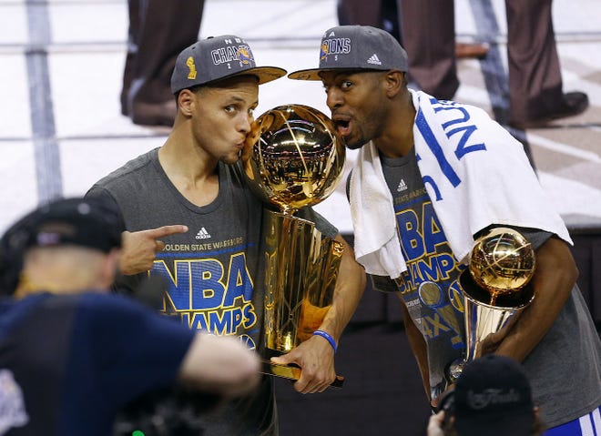 Golden State Warriors guard Stephen Curry, left, holds the championship trophy and Andre Iguodala holds the series MVP trophy as they celebrate winning the NBA Finals against the Cleveland Cavaliers in Cleveland, Wednesday, June 17, 2015. The Warriors defeated the Cavaliers 105-97 to win the best-of-seven game series 4-2.