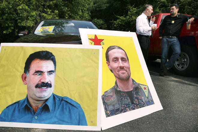 Necati Yuzbasioglu, of Manville, R.I., background left, talks with Ben Douthwaite, of Delaware, beside pictures of Keith Broomfield, right, and Kurdish leader Abdullah Ocalan outside Grace Baptist Church Wednesday in Hudson. The Associated Press