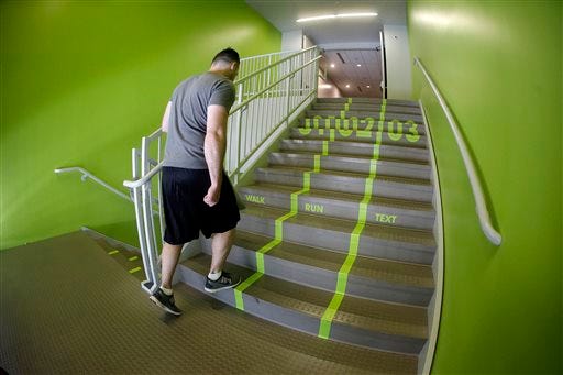 A Utah Valley University student walks up the bright green lanes painted on the stairs to the gym Thursday, June 18, 2015, at Utah Valley University, in Orem, Utah. Utah Valley University spokeswoman Melinda Colton said the green lanes were intended as a lighthearted way to brighten up the space and get students' attention. (AP Photo/Rick Bowmer)