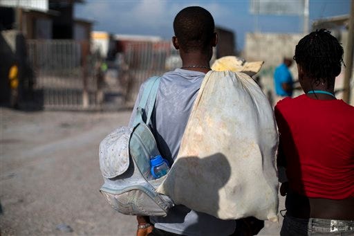 Jean Thezon, 26, left, stands with girlfriend Milene Monime, 16, as they look back toward the Dominican Republic border gate after being deported to Malpasse, Haiti, Wednesday, June 17, 2015. With tears in his eyes, Thezon said he had lived in the Dominican Republic since age four and didn't know where he, his girlfriend, and two-month-old son would go in Haiti. Authorities are prepared to resume deporting non-citizens without legal residency in the Dominican Republic after largely putting the practice on hold for a year, the head of the country's immigration agency said Tuesday. (AP Photo/Rebecca Blackwell)