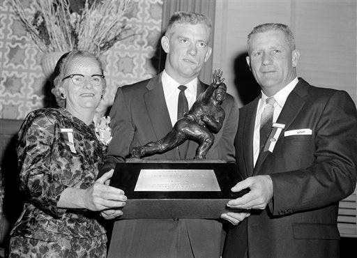 FILE - In this Dec. 12, 1957, file photo, John Crow, Texas A&M halfback, center, and his parents, Mr. and Mrs. Harry Crow of Springhill, La., hold Heisman Memorial Trophy award to Crow as the outstanding college football player of 1957 at dinner at the Downtown Athletic Club in New York. Crow, the bruising running back who won the 1957 Heisman Trophy with Texas A&M before a Pro Bowl career in the NFL, died Wednesday night, June 17, 2015, surrounded by his family, Texas A&M said. He was 79. (AP Photo/File)