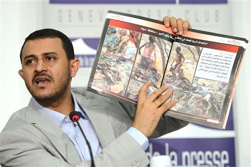Hamza al-Houthim head of the Houthi delegation, shows photographs of injured and killed children as he speaks on human rights during a press conference on the Yemen peace talks at the Geneva Press Club in Geneva, Switzerland, Thursday, June 18, 2015. (Martial Trezzini/Keystone via AP)