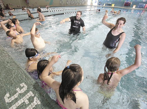 Massillon YMCA employees Isaiah Stanford and Donna Mash work on strokes with children during the global “World's Largest Swim Lesson” on Thursday.