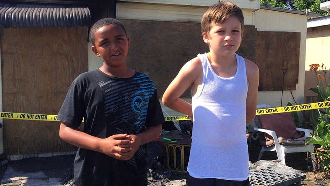 Isiah Francis, 10, left, and Jeremiah Grimes, 11, explain how they ran into a burning trailer at Lake John's Motel Efficiency on West Colonial Drive in Oakland, Fla., late Tuesday morning and rescued a toddler and a baby on June 16, 2015. (Tiffany Walden/Orlando Sentinel via AP) MAGS OUT; NO SALES