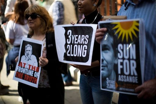 Supporters of WikiLeaks founder Julian Assange hold placards during a vigil across the street from the Ecuador embassy in London, Friday, June 19, 2015. Julian Assange is marking the third anniversary of his stay inside Ecuador's London embassy. The WikiLeaks founder entered the building on June 19, 2012, to avoid extradition to Sweden for questioning about alleged sexual assaults. British police stand outside, ready to arrest him if he leaves. (AP Photo/Matt Dunham)