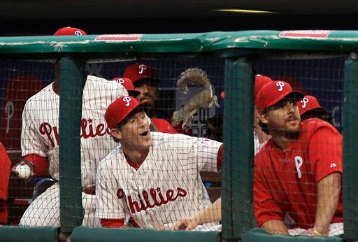 A squirrel leaps down into the Philadelphia Phillies' dugout near Chase Utley during the second inning of a baseball game against the St. Louis Cardinals, Friday, June 19, 2015, in Philadelphia. The squirrel climbed up the netting behind home plate and scurried along the support wire where it fell onto the Phillies dugout and then jumped down with the players.