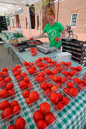 Shelby Siegenthaler of Wishwell Farms sets out tomatoes in her stand at the farmers market in New Albany's Market Square.