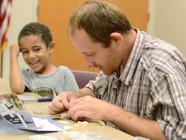 Izaiah Cannon, 4, looks as his father, Michael, carefully builds a platform for his toy at the Breakfast with Dad event Saturday at the Kinston-Lenoir County Public Library.