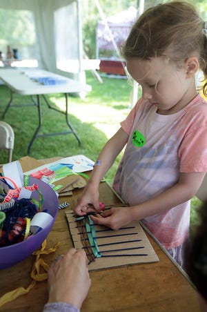 Lilly Weymouth, 5, of Hingham weaves a piece of art for herself in the kids tent during the 60th annual South Shore Arts Center Arts Festival on Saturday, June 20, 2015.