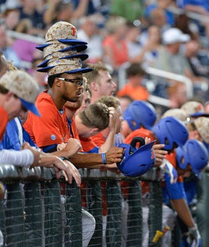 Florida's Buddy Reed wears a stack of rally caps in the dugout in the ninth inning of an NCAA College World Series baseball elimination game against Virginia in Omaha, Neb., Saturday, June 20, 2015. Virginia won 5-4 and advances to play Vanderbilt in the championship series. (AP Photo/Ted Kirk)