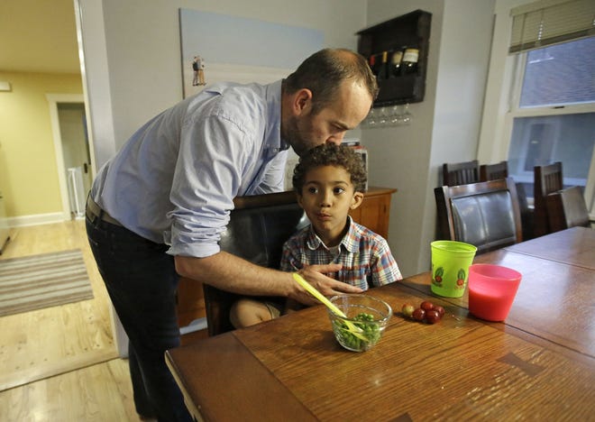 Weston Clark, kisses his son, Xander, 4, while he eats at their home in Salt Lake City. Fatherhood has been exhilarating for Clark, who put aside a teaching career to be a stay-at-home dad for a 4-year-old son and 17-month-old daughter adopted by him and his husband. ASSOCIATED PRESS PHOTOS