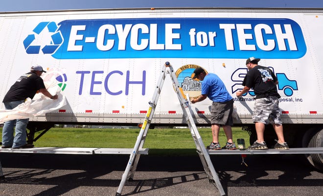 Lowen Graphic installers Alex Stillwell, left, Russ Stewart and Ray Carlson apply the new graphics to the E-Cycle for TECH trailer Monday morning, June 22, 2015, at the Lowen Corporation facility, 1111 Airport Rd. The semi will be located at the Reno County landfill which will make it easier for people to recycle their electronic equipment.