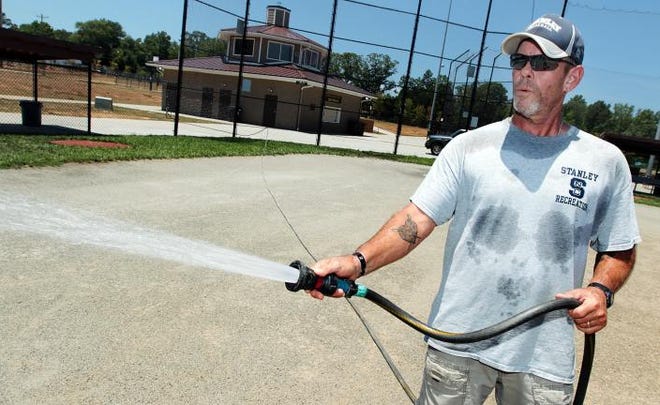 (Photo Mike Hensdill/The Gaston Gazette ) Richard O'Brien, with the Stanley Recrestion Department, wets down the ball fields at Harper Park on Blacksnake Road in Stanley Monday afternoon, June 22, 2015 with temps reaching into the high 90s.