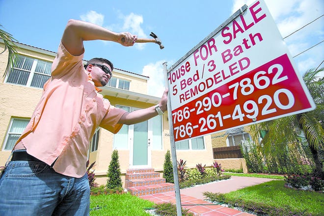 In this Friday, April 24, 2015 file photo, Robert Almirall, director of marketing and special assets coordinator for Mederos & Associates Real Estate Inc., puts up a sign in front of a home in the Shenandoah neighborhood of Miami. More Americans bought homes in May, the National Association of Realtors reported Monday, June 22, 2015, a sign of economic strength that is pushing up average prices. (AP Photo/Wilfredo Lee, File)