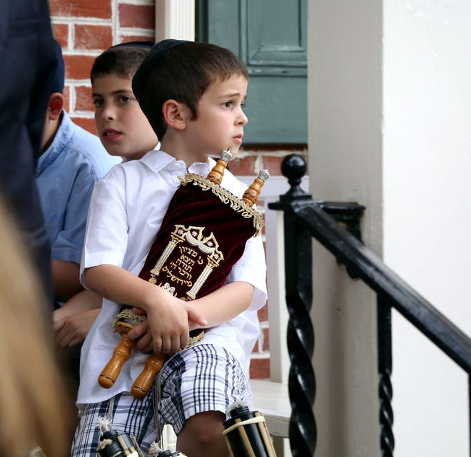 Zev Kahan holds a small Torah while standing in front of the Medford Community Center before the Torah parade.