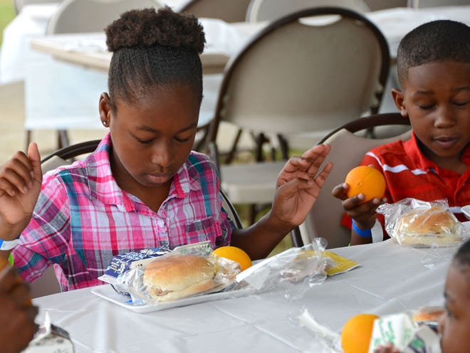 Kiayah Williams, 10, pauses before opening her lunch provided at the event. The Jacksonville Children's Commission led the statewide kickoff of the Summer Food Service Program on Tuesday, June 9, 2015 at A. Philip Randolph Heritage Park in Jacksonville, FL. It was the first time the city has been selected by the Florida Department of Agriculture and Consumer Services to lead the annual kick-off. Former Jaguars quarterback David Garrard joined JCC and USDA leadership in feeding local children.