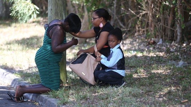 A woman and a child try to comfort another woman who mourns at the scene of a double homicide reported at 1208 17th Avenue N in Lake Worth, Sunday, June 21, 2015. (Damon Higgins / The Palm Beach Post)