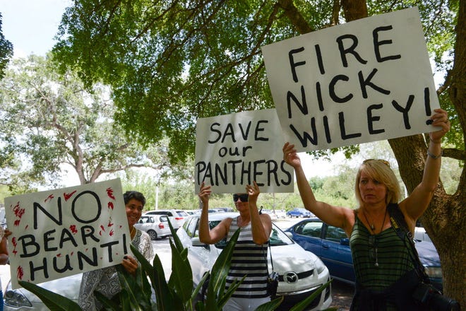 Donna Baez, Patty Kent and Terrie Dahl Thomas hold up signs during a news conference in front of the Hyatt Regency Sarasota that criticized state proposals dealing with black bears, Florida panthers and the use of state parks.