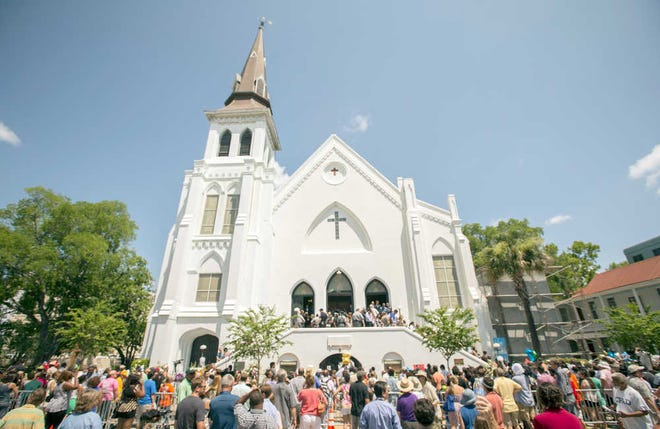 Stephen B. Morton/The Associated Press People stand outside as parishioners leave the Emanuel A.M.E. Church on Sunday in Charleston, four days after a mass shooting at the church claimed the lives of its pastor and eight others. -AP