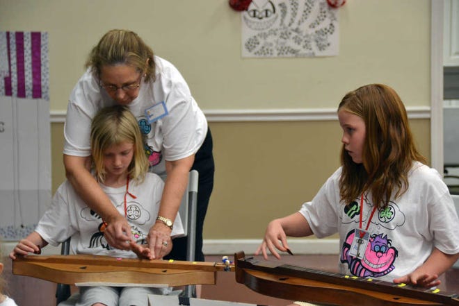 DeeAnna Wilkerson/The Sun Today Pat Van Houten, president of the Friends of the Girl Scouts group in Sun City, helps a local Girl Scout learn how to play the dulcimer.